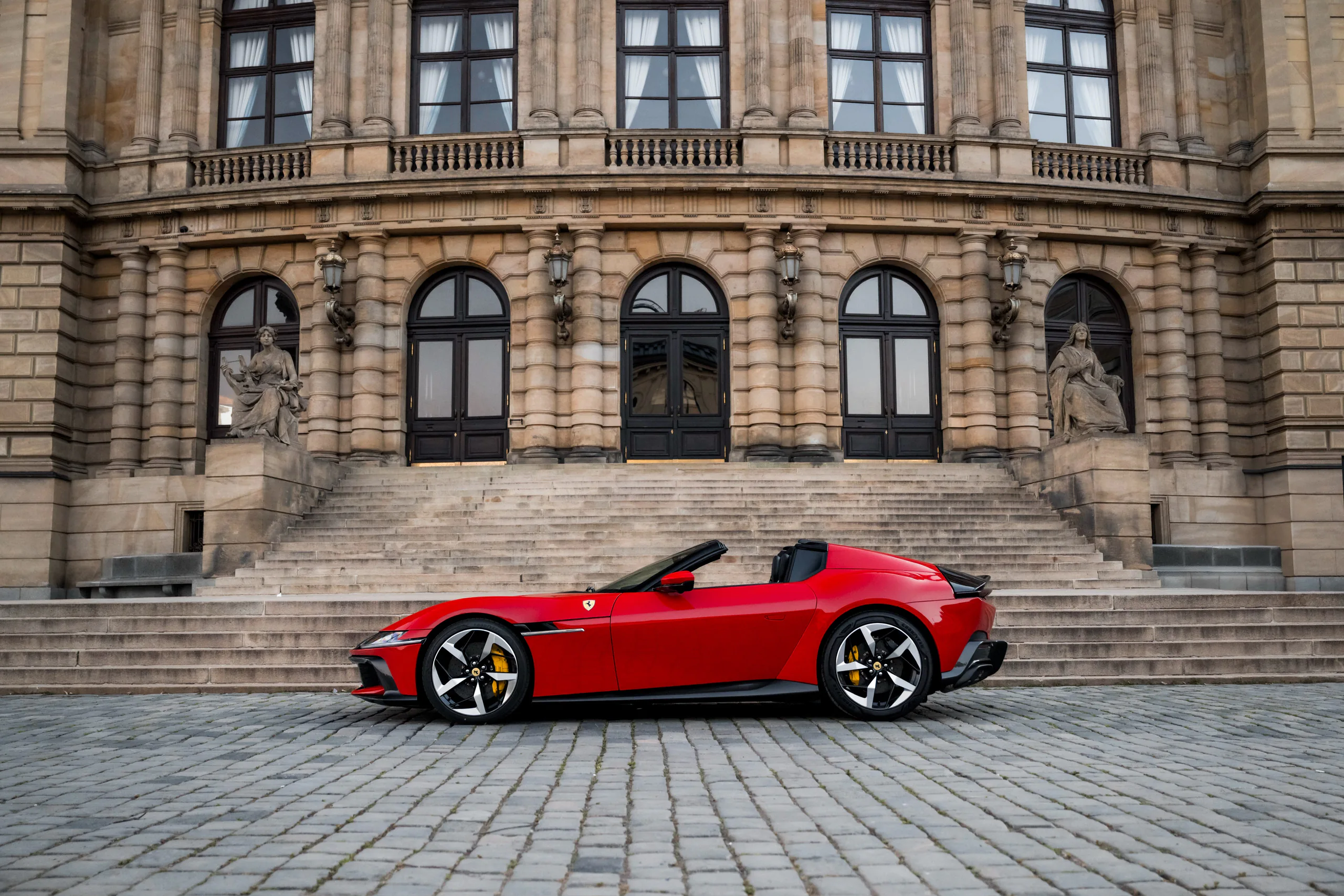 Red Ferrari 12Cilindri Spider in profile before the Rudolfinum steps