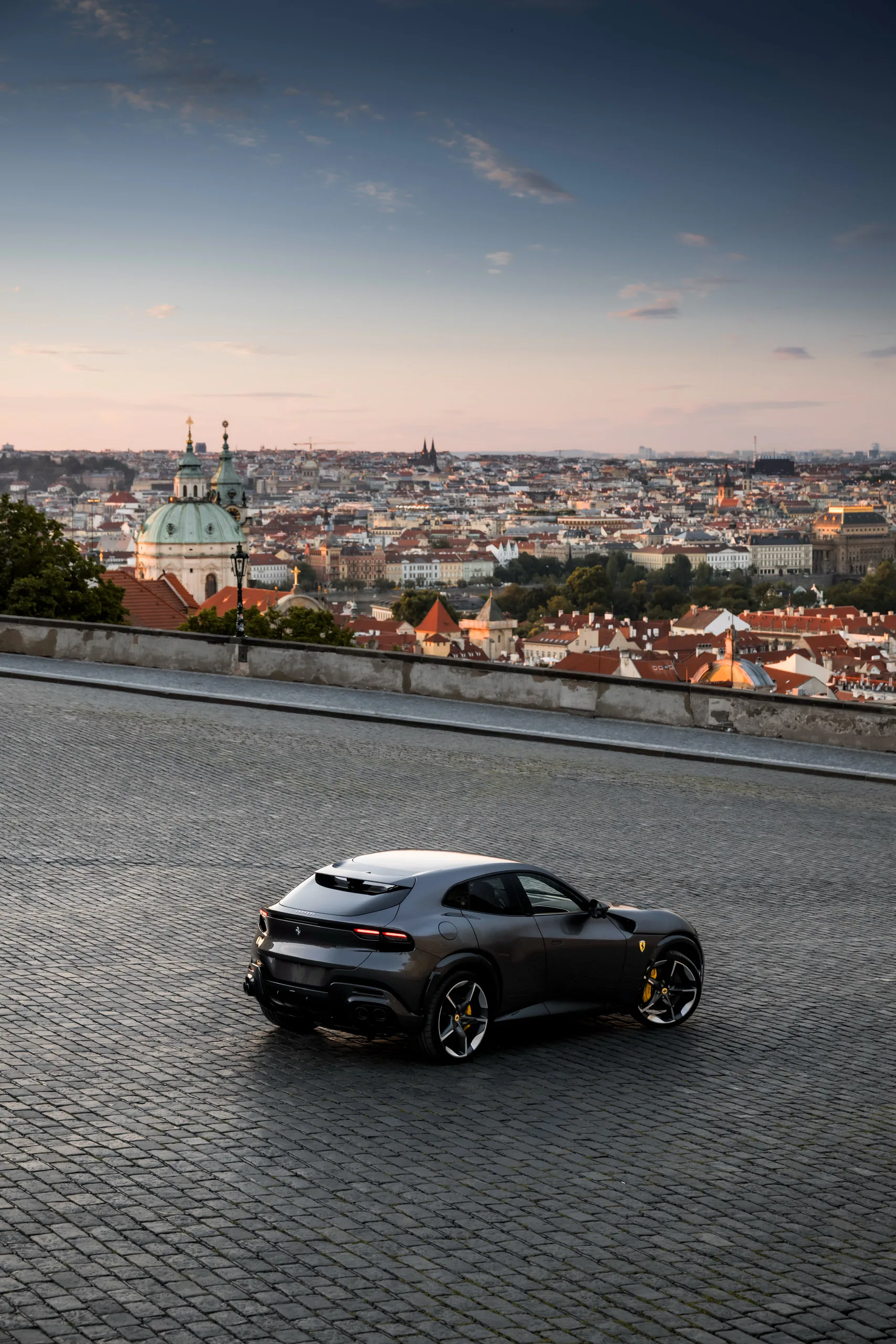 Ferrari Purosangue overlooking the Prague skyline at dusk